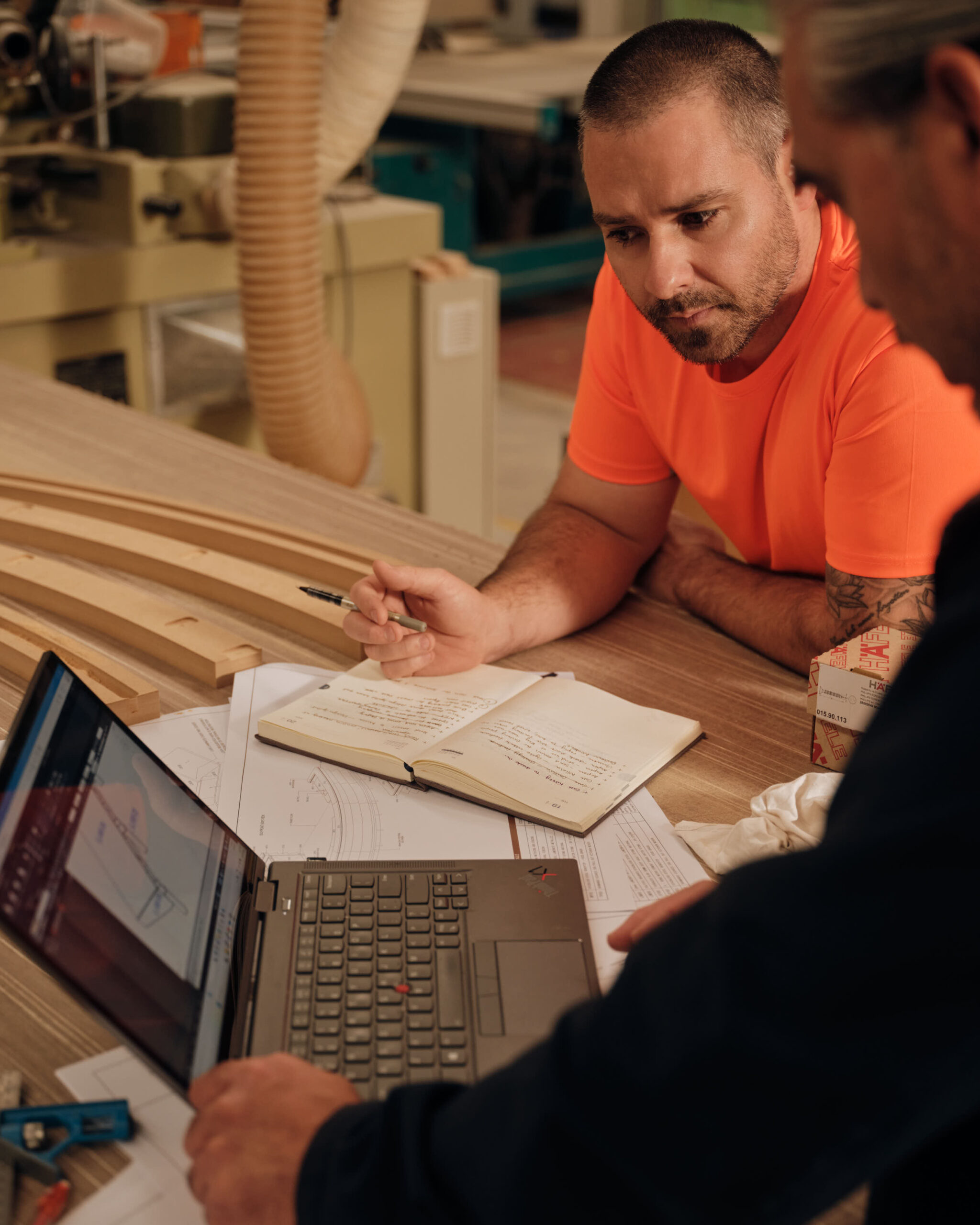 Two people discussing plans at a wood shop table